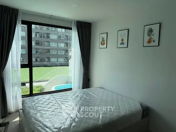 Bright bedroom with large window and pool view in modern apartment