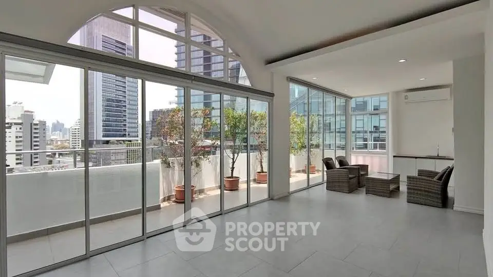 Spacious modern living room with large windows and city view, featuring a big balcony for outdoor relaxation.