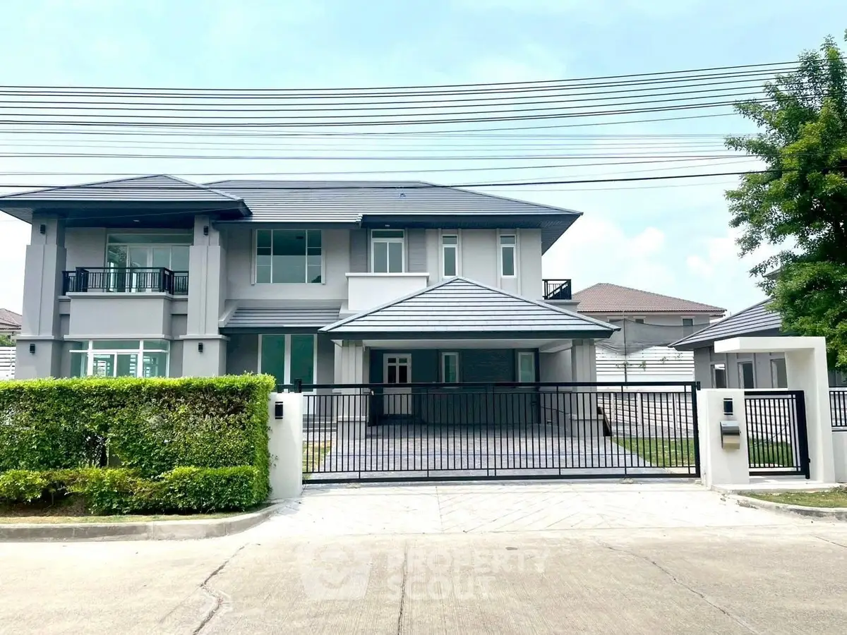 Luxurious modern two-story house with gated entrance and lush greenery