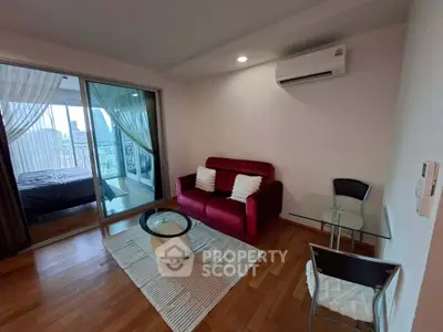 Modern living room with red sofa, glass table, and city view balcony in stylish apartment.