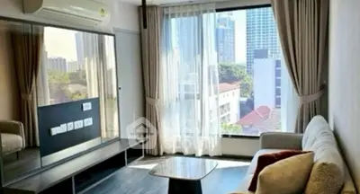 Modern living room with large window and city view, featuring sleek furniture and air conditioning.