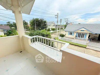 Charming balcony view in a serene suburban neighborhood with lush greenery and cozy homes.