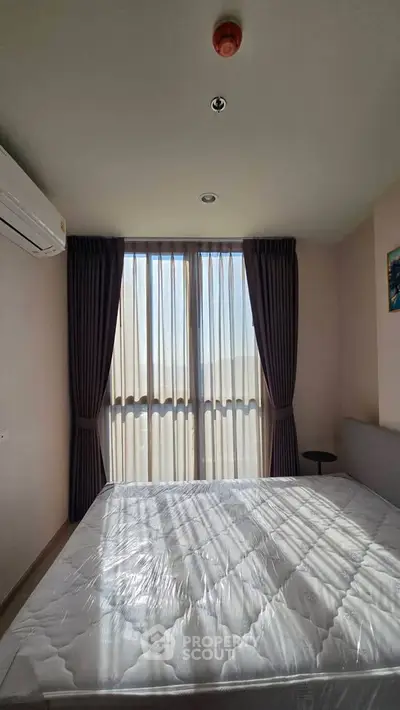 Bright bedroom with large window and modern furnishings in a stylish apartment.