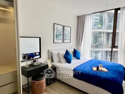 Modern bedroom with blue accents and city view from large window