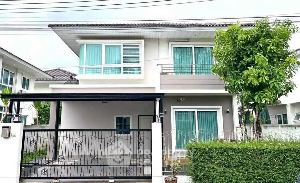 Modern two-story house with balcony and lush greenery in a serene neighborhood.