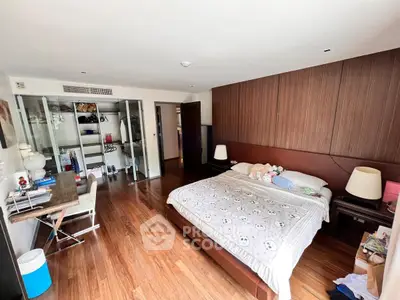 Spacious bedroom with wooden flooring and modern decor, featuring a cozy bed and ample storage space.