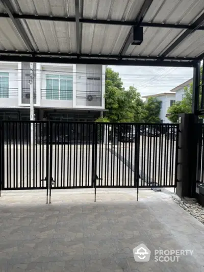 Modern gated entrance with sleek metal design and spacious driveway