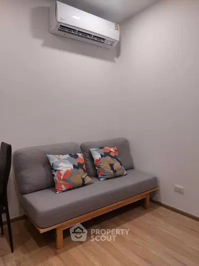 Cozy living room with modern sofa and air conditioning unit, perfect for relaxation.