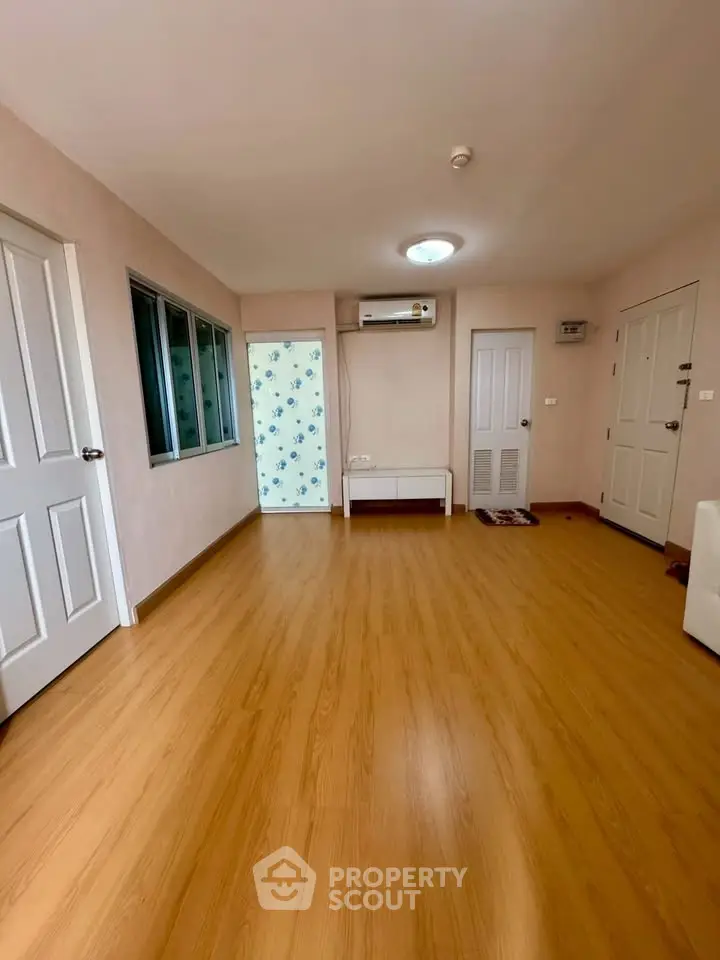 Spacious living room with wooden flooring and modern air conditioning unit.