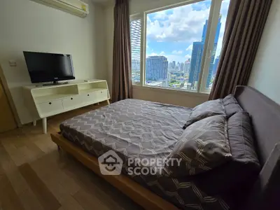 Modern bedroom with city view, featuring a stylish bed and TV stand, perfect for urban living.