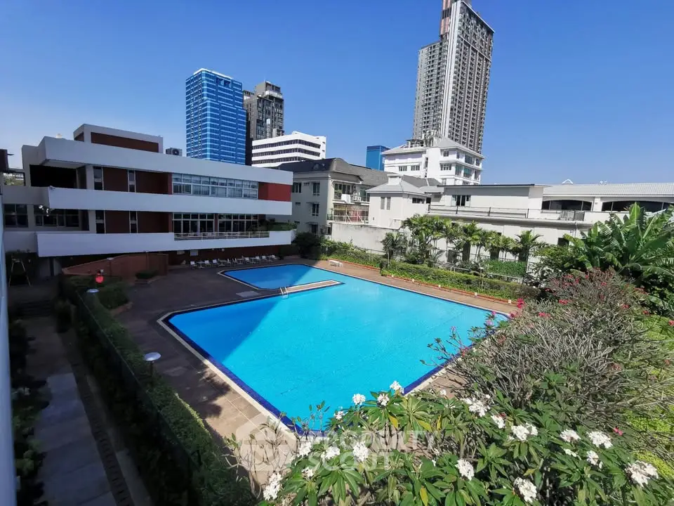 Luxurious urban apartment complex with stunning pool and city skyline view.