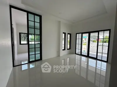 Spacious modern living room with large windows and sliding glass doors, offering abundant natural light.