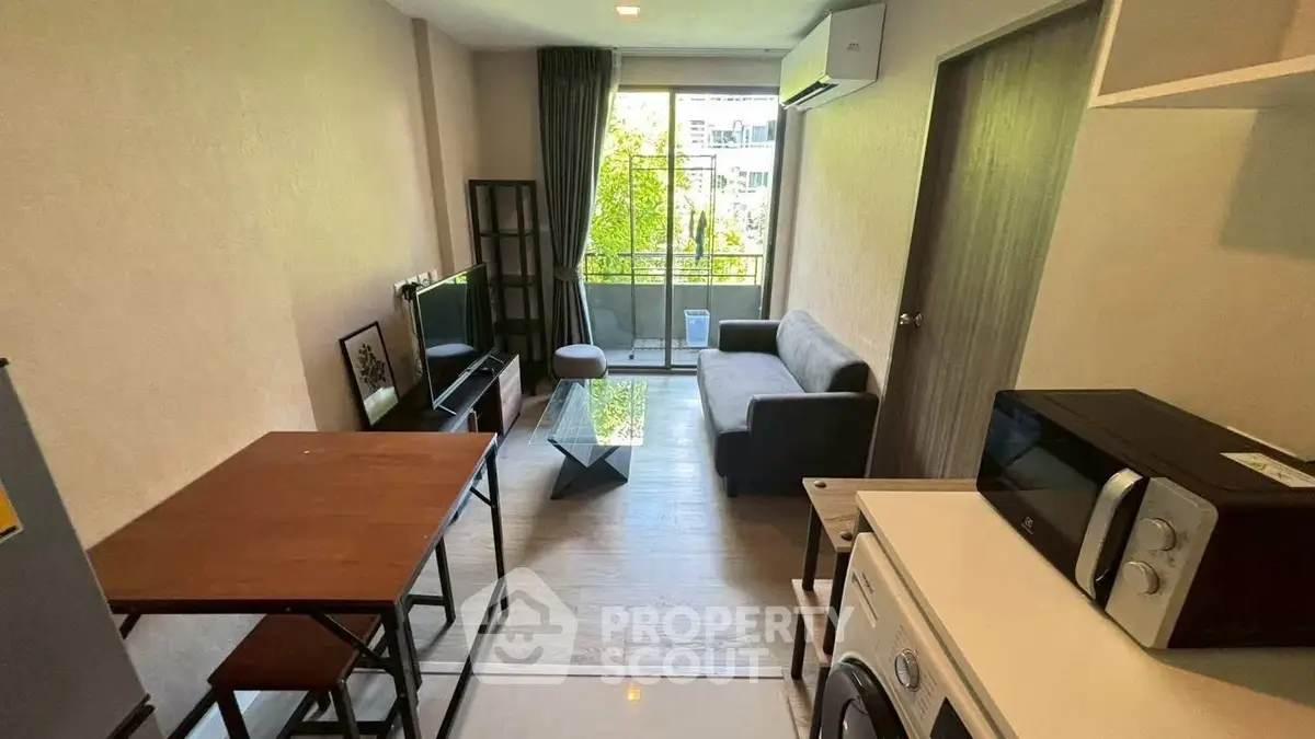 Modern living room with balcony, featuring sleek furniture and appliances, ideal for urban living.