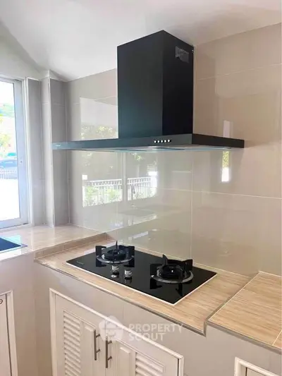 Modern kitchen with sleek gas stove and stylish range hood, perfect for culinary enthusiasts.