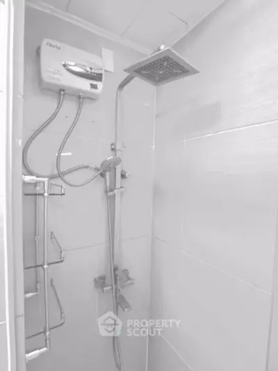 Modern bathroom shower with sleek fixtures and water heater in a stylish tiled setting.