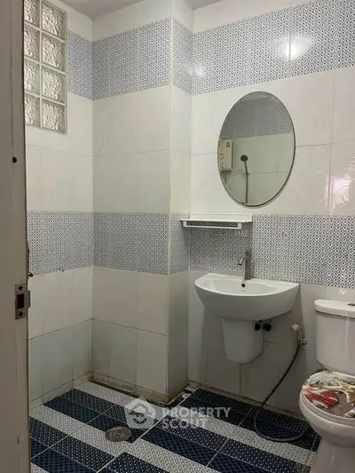 Modern bathroom with stylish blue and white tiles, featuring a round mirror and sleek fixtures.