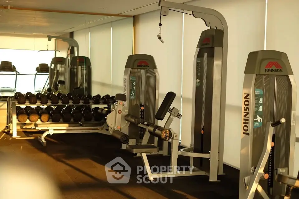 Modern gym with state-of-the-art fitness equipment and weights in a luxury building.