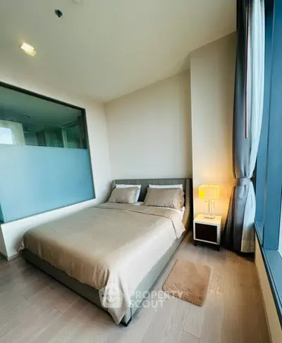 Modern bedroom with large window and stylish decor in a high-rise apartment.