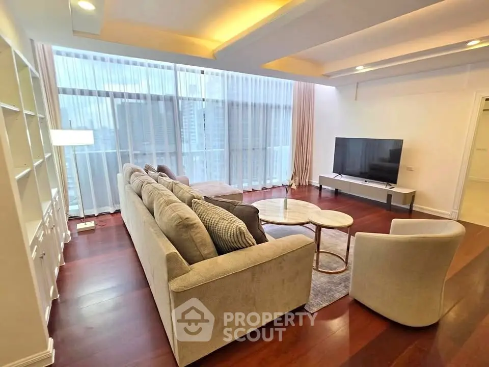 Spacious modern living room with large windows and elegant furniture in a high-rise apartment.