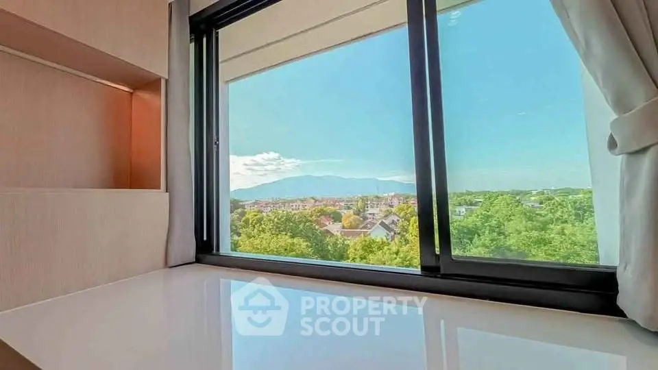 Bright room with large window offering stunning mountain and city view.