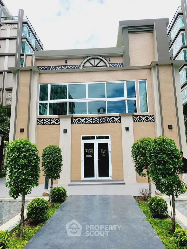Modern two-story building with large windows and landscaped entrance in urban setting.