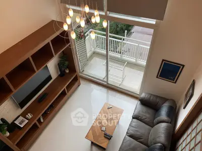 Spacious living room with modern chandelier and balcony access, perfect for relaxation and entertainment.