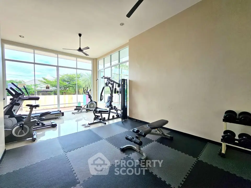 Spacious home gym with modern equipment and large windows for natural light.