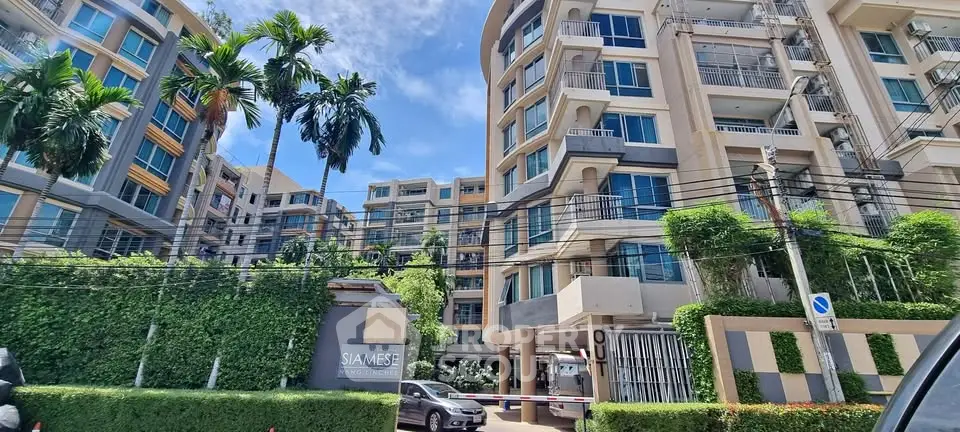 Modern condominium building with lush greenery and clear blue sky, showcasing urban living at its finest.