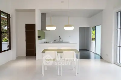 Modern minimalist kitchen with open layout and sleek dining area, featuring white and green accents.