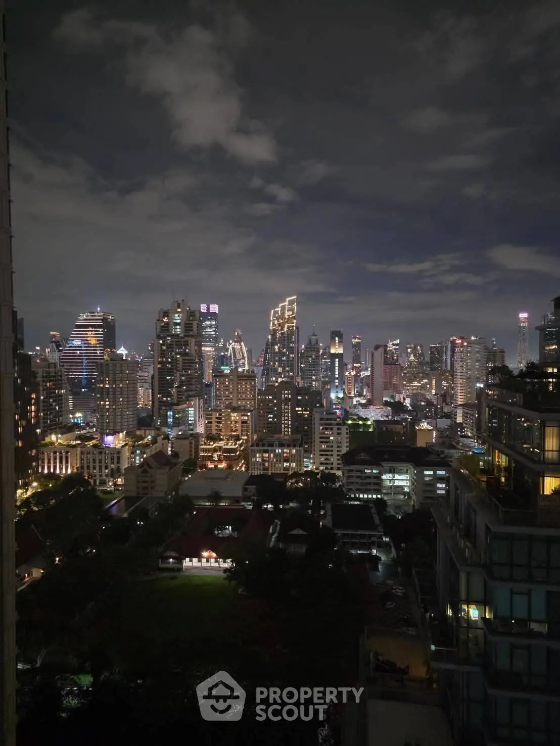Stunning city skyline view from a high-rise building at night, showcasing vibrant urban lights.