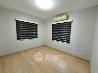 Spacious bedroom with wooden flooring and modern window blinds, perfect for a cozy retreat.