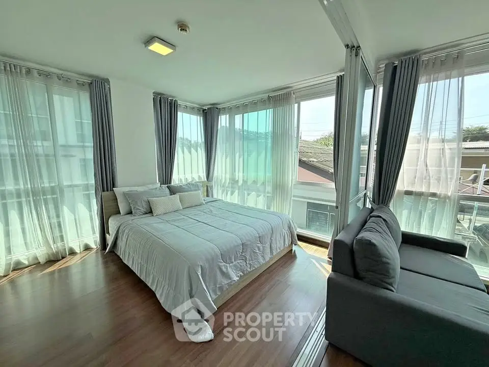 Spacious bedroom with large windows and cozy seating area