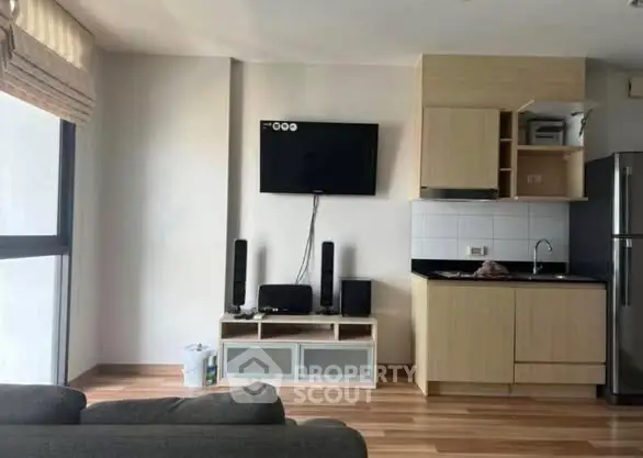 Modern living room with sleek TV setup and compact kitchen area.