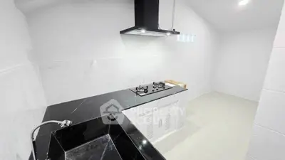 Modern kitchen with sleek black countertops and gas stove in a minimalist design.