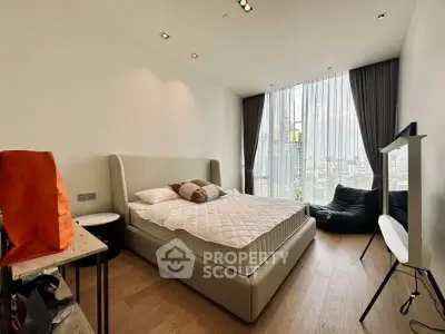 Modern bedroom with city view, featuring stylish furniture and floor-to-ceiling windows for natural light.