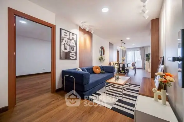 Modern living room with stylish decor and open layout, featuring a cozy blue sofa and elegant dining area.