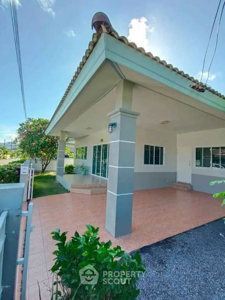 Charming single-story home with spacious front porch and lush garden, perfect for family living.