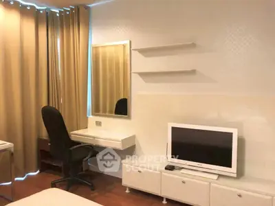 Modern bedroom with TV, desk, and mirror, featuring elegant curtains and wooden flooring.