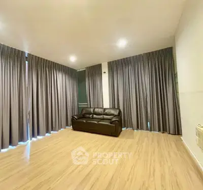 Spacious living room with wooden flooring and elegant curtains