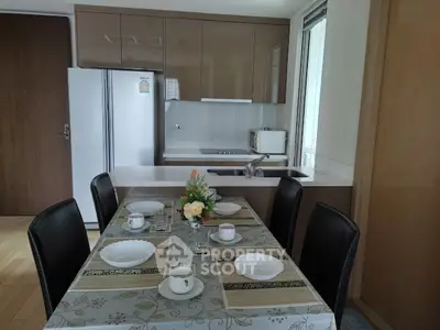 Modern kitchen with dining area featuring sleek cabinetry and elegant table setting.