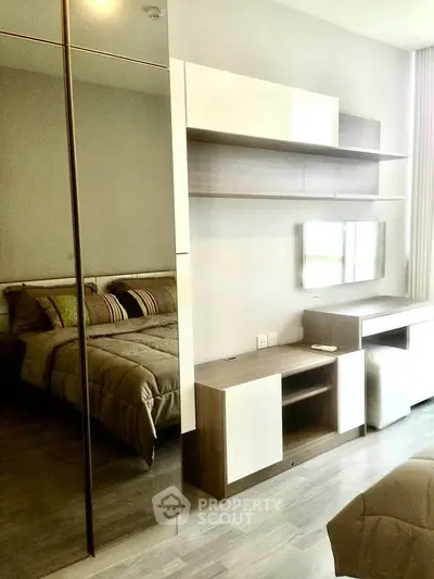 Modern bedroom with sleek furniture and mirrored wardrobe in a stylish apartment.