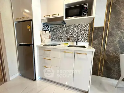 Modern kitchen with sleek white cabinets, mosaic backsplash, and built-in appliances in a stylish apartment.