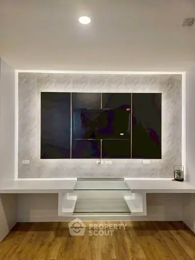 Modern living room with sleek built-in entertainment center and stylish wood flooring.