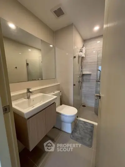 Modern bathroom with sleek fixtures and glass shower enclosure in a contemporary apartment.