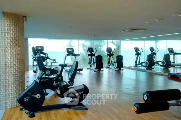 Spacious gym with modern equipment and panoramic sea view windows.