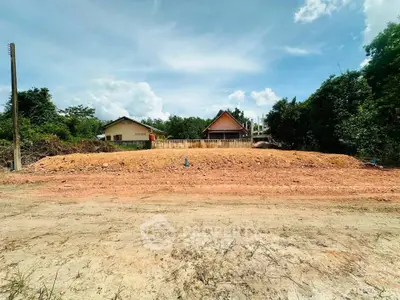 Vacant land plot with potential for development, surrounded by lush greenery and clear skies.