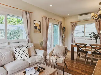 Charming living room with cozy decor and natural light, featuring a dining area and stylish furnishings.