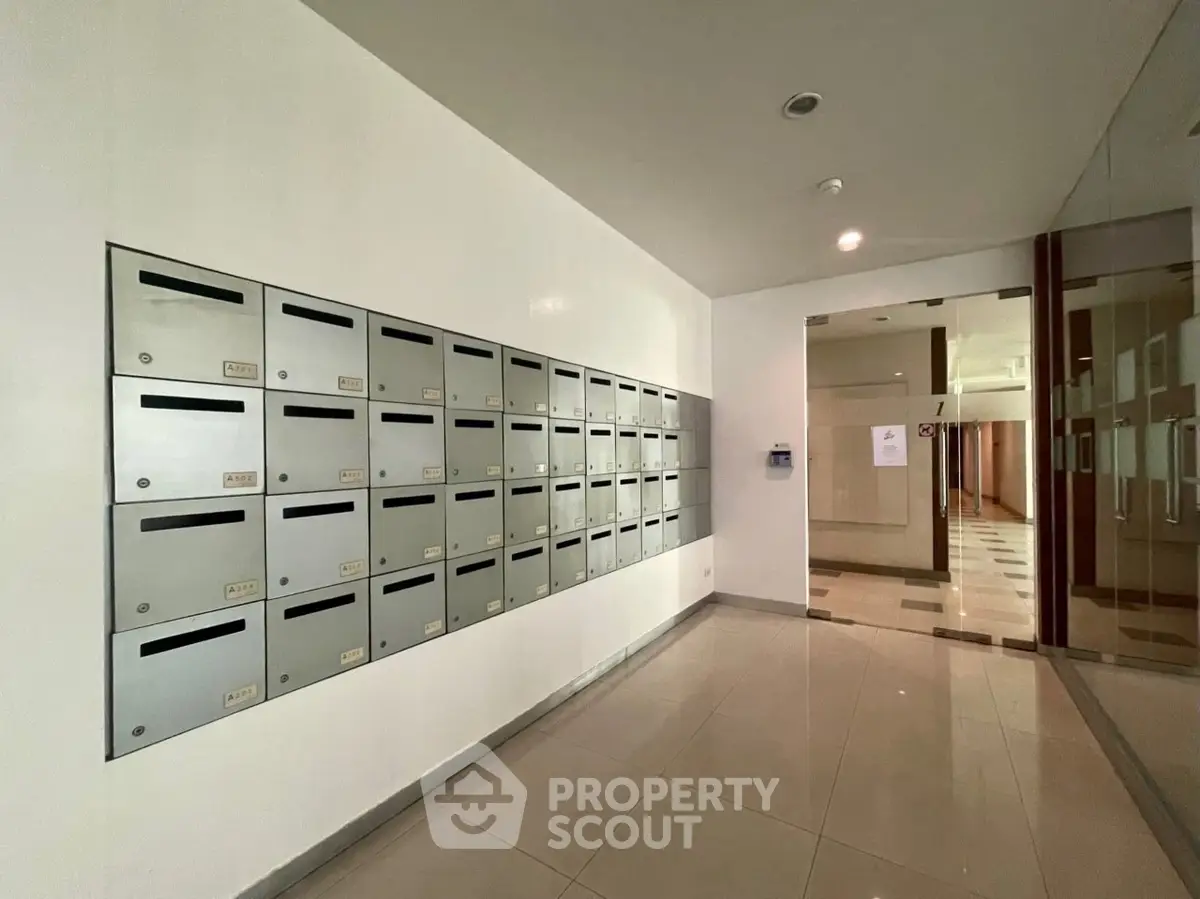 Modern apartment building entrance with sleek mailboxes and polished tile flooring.