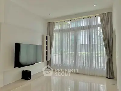 Spacious modern living room with large window and mounted TV, perfect for relaxation.