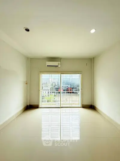 Spacious empty room with large window and air conditioning, perfect for customization.